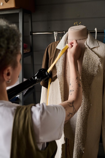 Foto giovane sarta o designer femminile creativo di vestiti che prendono le misure del cappotto
