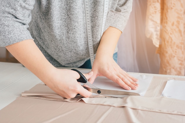 Young seamstress makes clothes cutting fabric