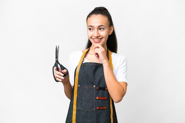 Young Seamstress woman over isolated white background looking to the side and smiling