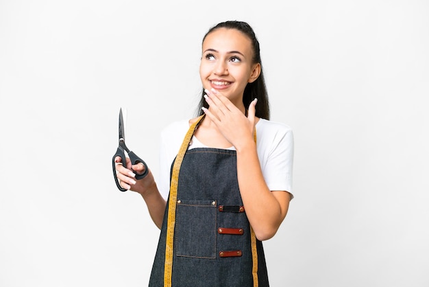 Young Seamstress woman over isolated white background looking up while smiling