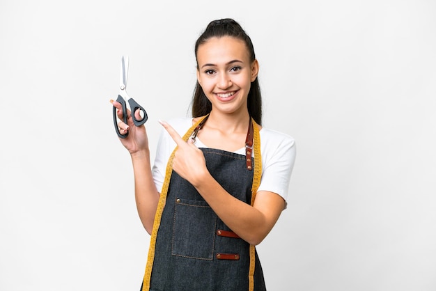 Young Seamstress woman over isolated white background pointing to the side to present a product