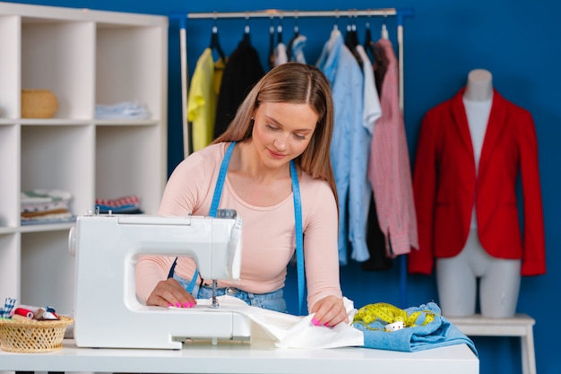 Young seamstress working on her sewing machine on textile factory