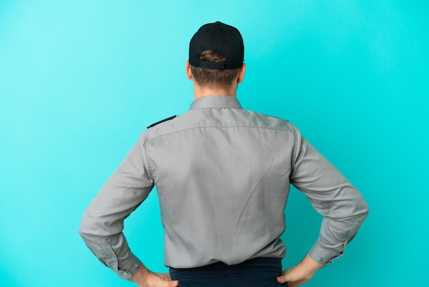 Young security man isolated on blue background in back position