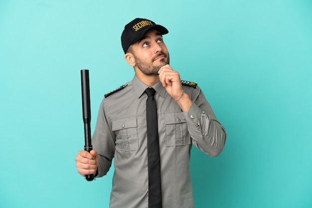 Young security man isolated on blue background and looking up