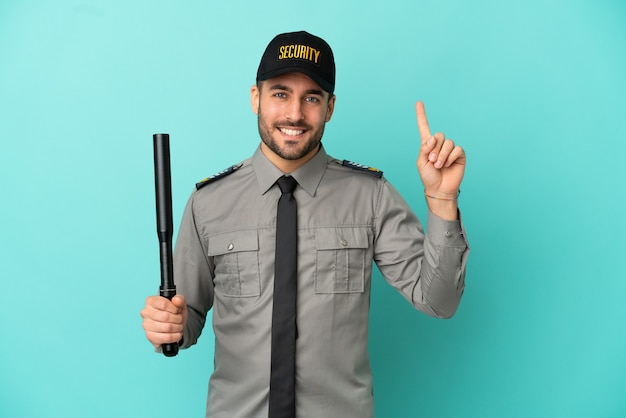 Young security man isolated on blue background pointing up a great idea