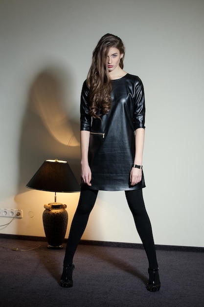 Young seductive woman in a black leather dress