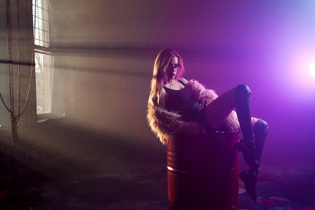 Young seductive woman, portrait in darkness. Girl in stylish pink fur coat and glasses.