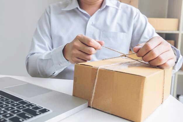 Young seller man preparing package to be sent