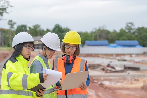 若くて上級のエンジニアが建設中の大きな建物の仕事について話し合う建設中の現場で働く3人