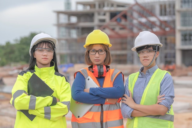 若くて上級のエンジニアが建設中の大きな建物の仕事について話し合う建設中の現場で働く3人