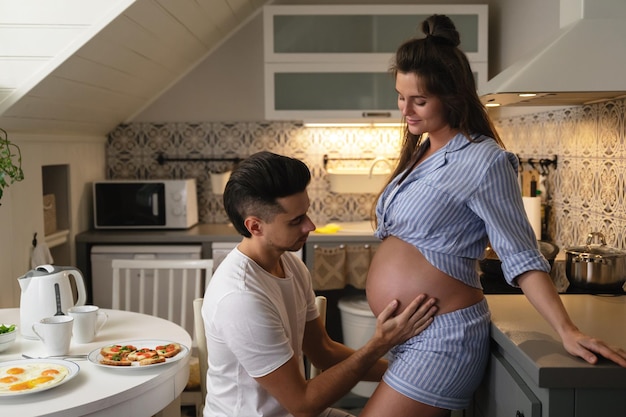 Young and sensual couple waiting for a baby husband and his\
pregnant wife during breakfast time