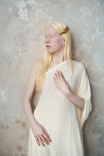 Young serene albino woman with closed eyes standing by marble wall