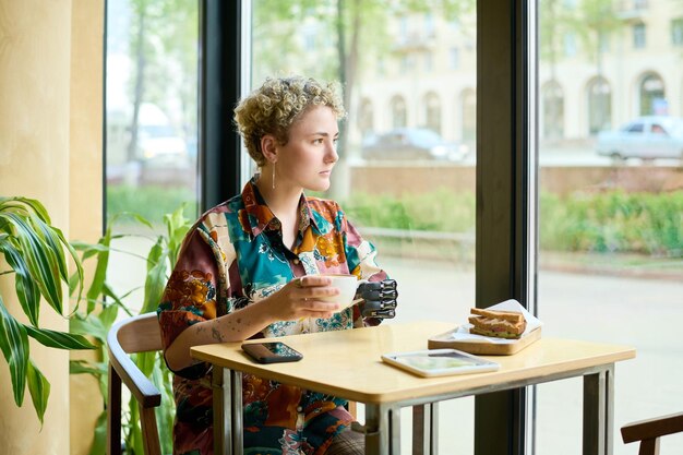 Young serene female with physical impairment looking through large window