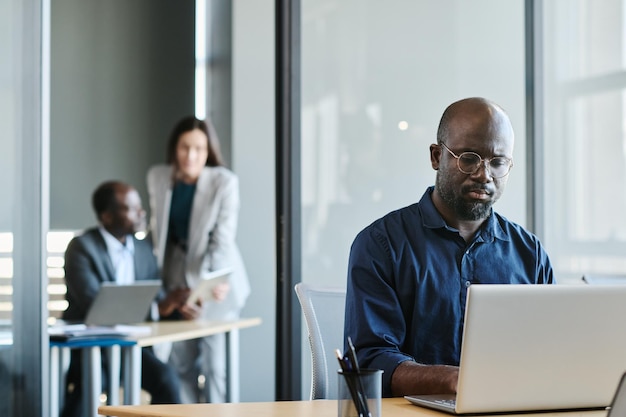 Young serious African American analyst looking at laptop screen