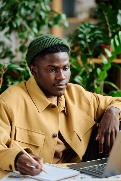 Young serious african american manager making notes in front of laptop