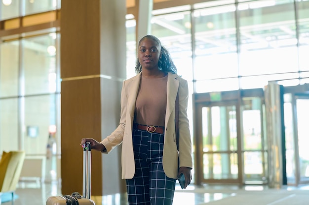 Young serious african american woman in smart casualwear standing in lounge