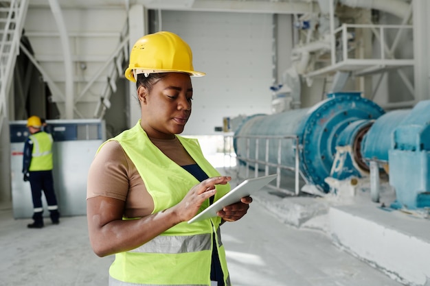 Young serious black woman with tablet looking through online data