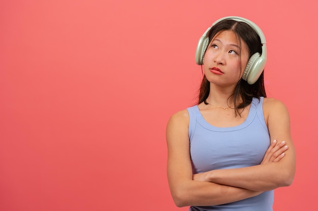 音楽を聴くピンクの背景で孤立した真剣な若い中国人女性