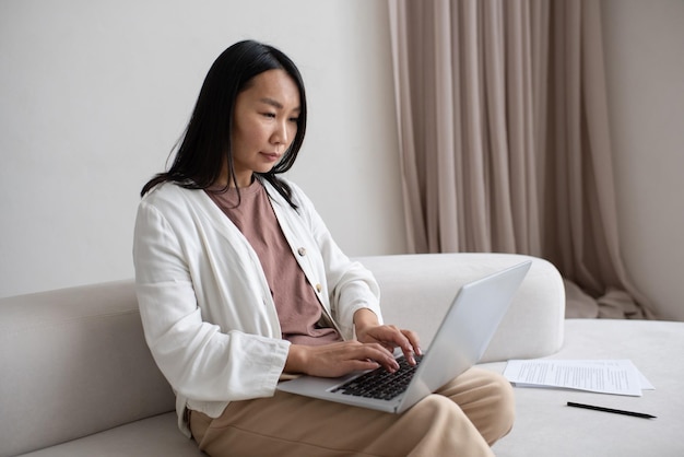 Young serious employee with laptop on her knees concentrating on network