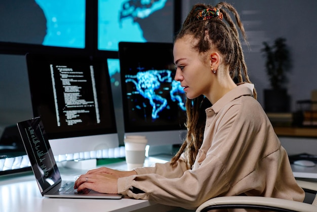 Молодая серьезная женщина-ИТ-менеджер печатает на клавиатуре ноутбука в офисе