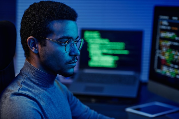 Young serious it support engineer in eyeglasses looking at\
computer screen