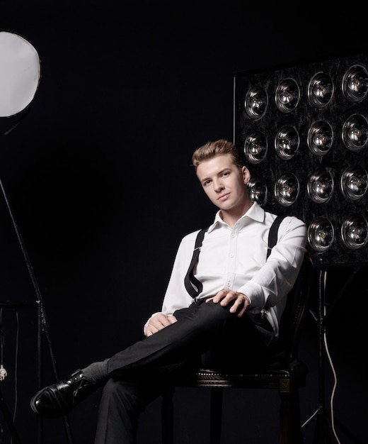 Young serious man on chair, close-up portrait, fashion model