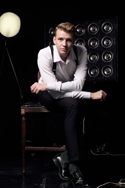 Young serious man on chair, close-up portrait, fashion model