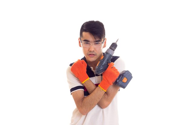 Young serious man holding grey electric screwdriver on white background in studio