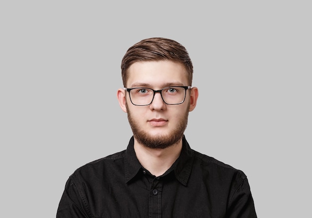 Young serious man with stylish neat beard, wearing a black shirt and in glasses