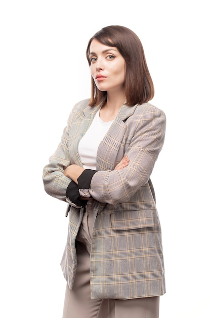 Young serious teacher or businesswoman crossing arms by chest while standing in isolation