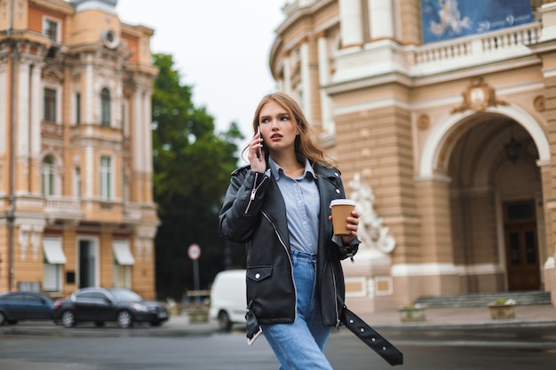 Young serious woman in leather jacket and jeans thoughtfully 