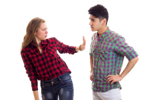 Young serious woman with young handsome man with dark hair in plaid shirts arguing
