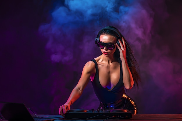 Young sexy DJ with sunglasses playing music