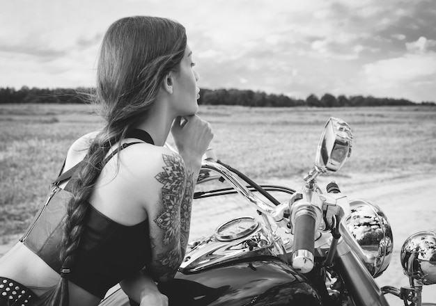 Молодая сексуальная девушка позирует на мотоцикле на закате. Концепция автоспорта. Смешанная техника