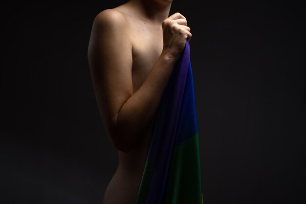 Young sexy nude gay man holding rainbow lgbt community flag on\
black background