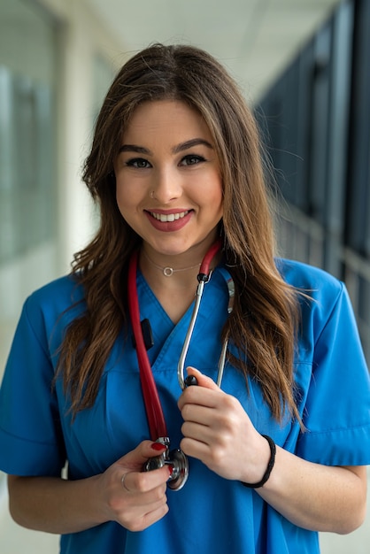 Young sexy nurse or femele doctor in blue uniform posing on modern hallway clinic. healthcare