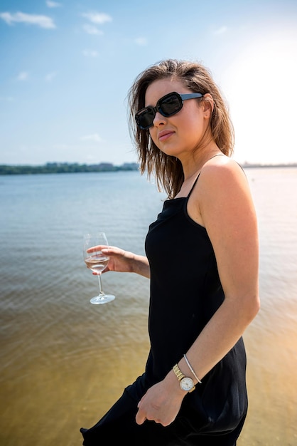 Young sexy woman in black dress walking of the lake