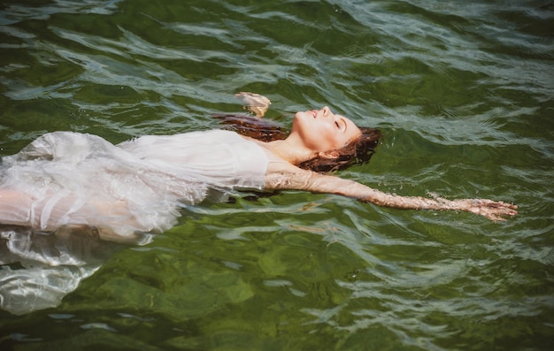 Young sexy woman is swimming in the transparent blue sea sensual slim woman floating on the water of