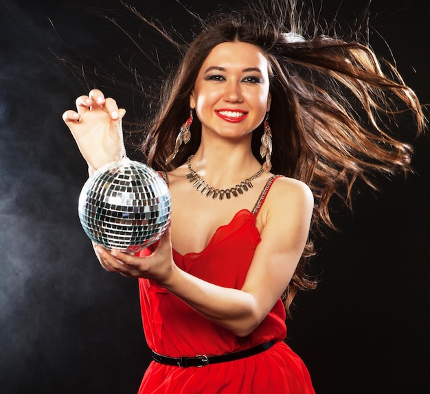 Young sexy woman in red dres keeping disco ball