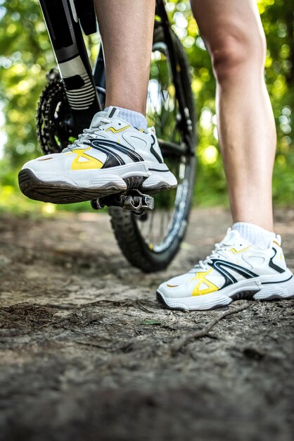 若いセクシーな女性は緑のショートドレスを着て森の中で自転車に乗る夏の日に自由な時間を過ごす活動ライフスタイル