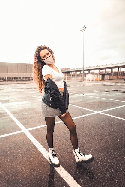 Young sexy woman with a white mask on a parking lot