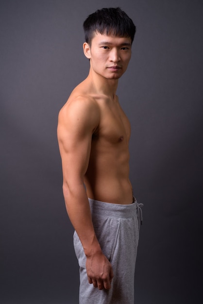 Young shirtless man against gray