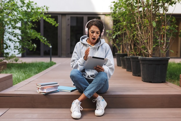 Young shocked lady in headphones sitting and amazedly 