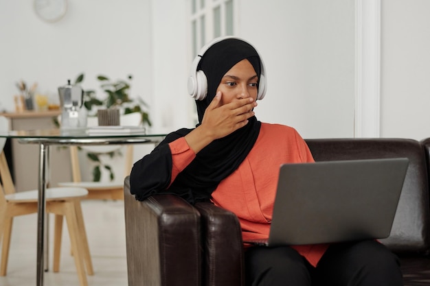 Photo young shocked muslim woman in hijab covering her mouth by hand