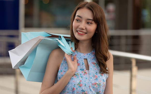 Молодая женщина покупок держа бумажные сумки на торговом центре, путешествуя концепция покупок.