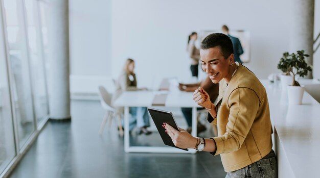 Photo young short hair business woman standing in the office and using digital tablet in front of her team