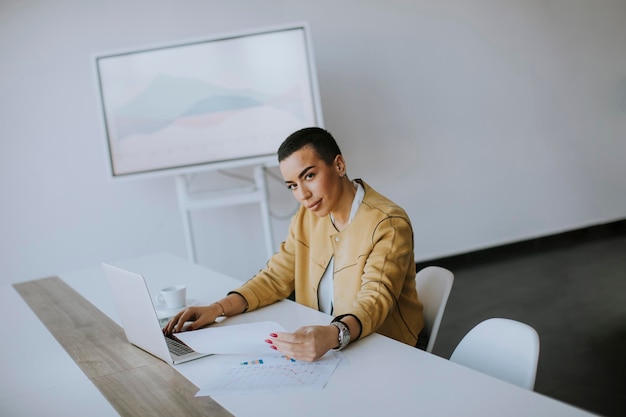 Young short hair woman working on laptop while sitting at the office