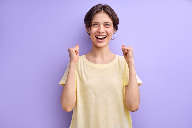 Young short haired cute woman cheering carefree and excited celebrating win victory concept isolated...