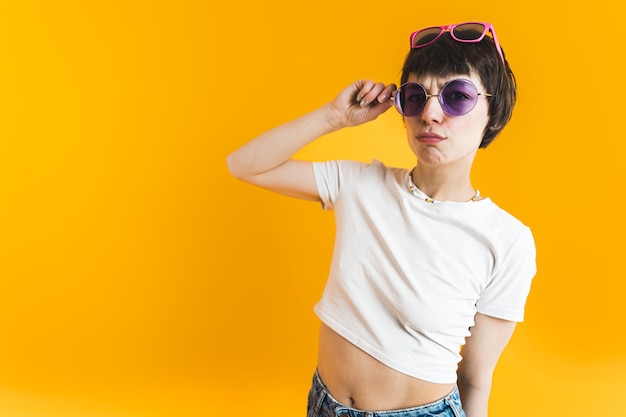 Young shorthaired woman wearing multiple pairs of sunglasses and looking at camera confused studio