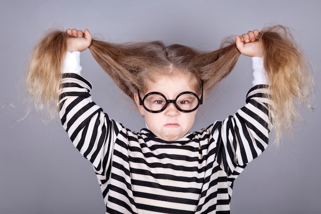 Photo young shouting child in glasses and striped knitted jacket.